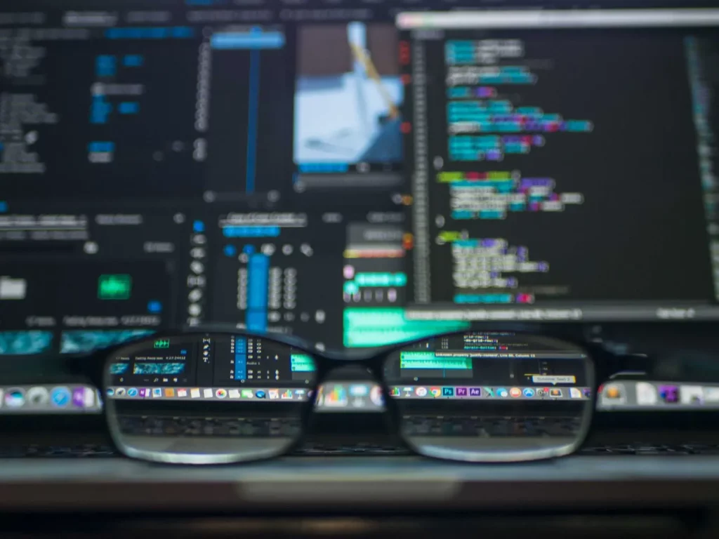 Glasses in front of a computer screen with open programs that are not in focus. You can see part of the screen clearly through the lenses.