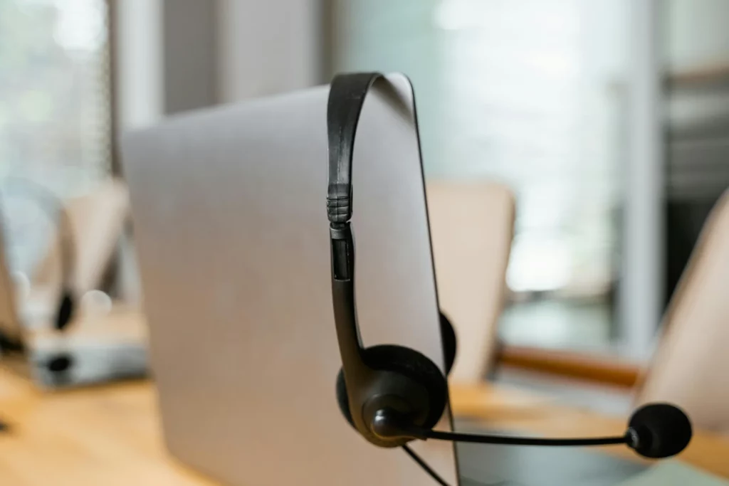 A Macbook photographed from behind with a headset hanging over its screen.